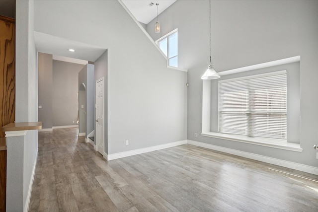 unfurnished dining area with a high ceiling and light wood-type flooring