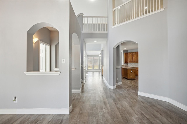 hallway featuring a towering ceiling and light hardwood / wood-style flooring