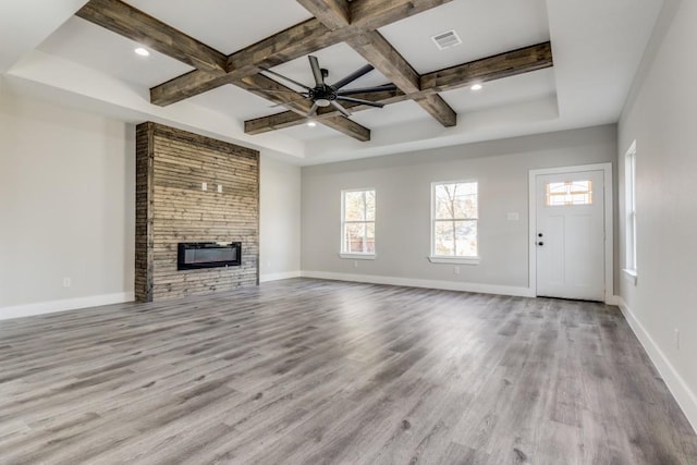 unfurnished living room with beam ceiling, light wood-type flooring, and coffered ceiling