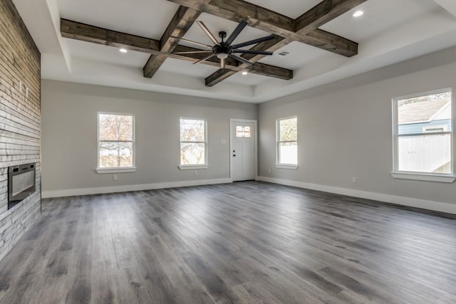 unfurnished living room with coffered ceiling, a brick fireplace, ceiling fan, beamed ceiling, and dark hardwood / wood-style flooring