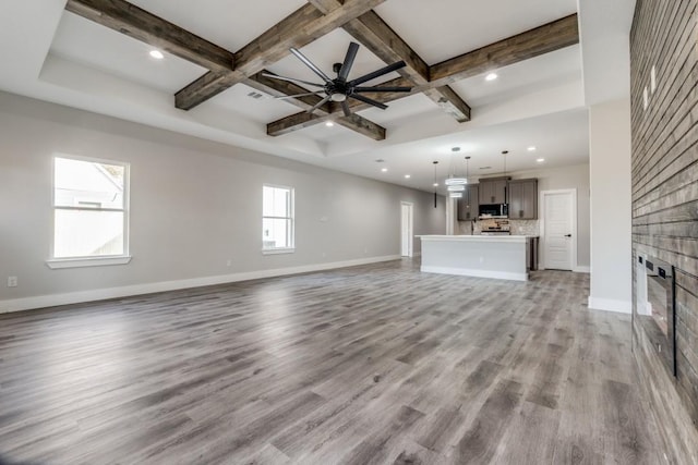 unfurnished living room with a fireplace, coffered ceiling, ceiling fan, light hardwood / wood-style flooring, and beamed ceiling