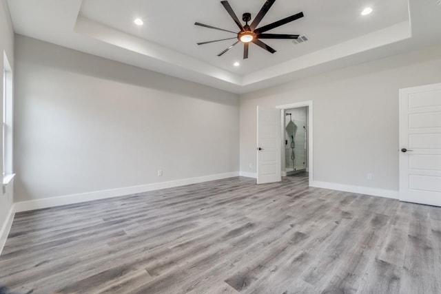 interior space with ceiling fan, light wood-type flooring, and a tray ceiling