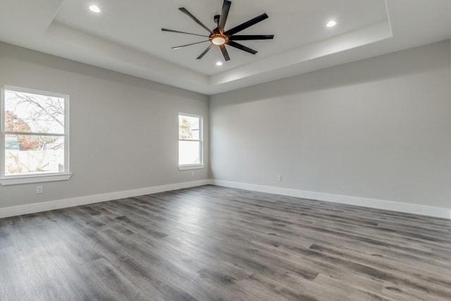 empty room with hardwood / wood-style floors, a tray ceiling, and ceiling fan