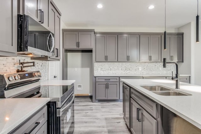 kitchen with backsplash, sink, hanging light fixtures, and appliances with stainless steel finishes