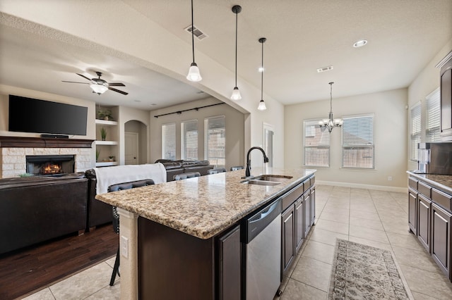 kitchen featuring a fireplace, visible vents, stainless steel dishwasher, light tile patterned flooring, and a sink