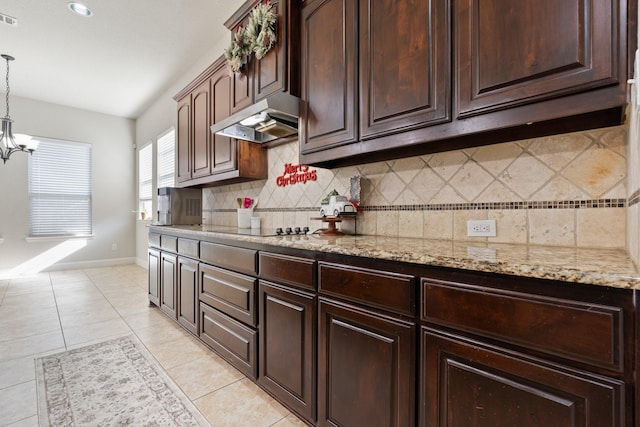 kitchen with dark brown cabinetry, black electric stovetop, tasteful backsplash, light tile patterned flooring, and decorative light fixtures