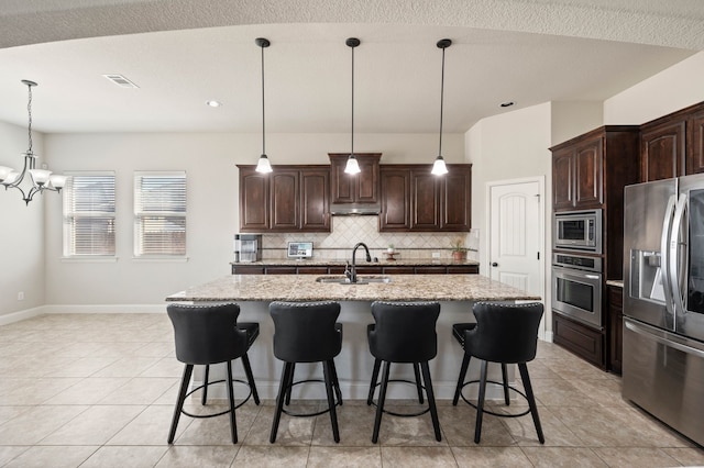 kitchen with stainless steel appliances, tasteful backsplash, visible vents, a sink, and dark brown cabinets