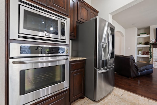 kitchen with appliances with stainless steel finishes, dark brown cabinets, and light tile patterned floors