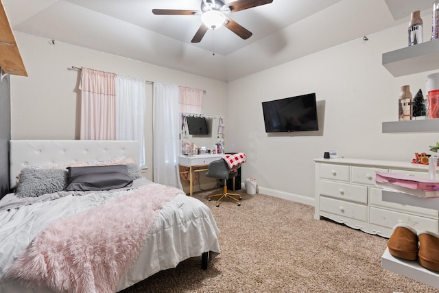 carpeted bedroom with ceiling fan and a tray ceiling