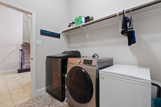 laundry room with laundry area, light tile patterned floors, baseboards, and separate washer and dryer