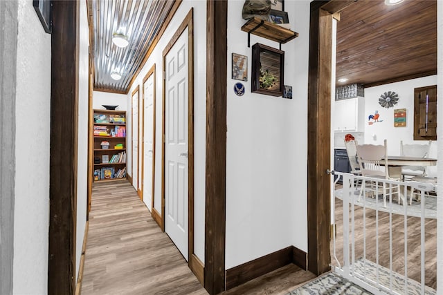 hall featuring light wood-type flooring and wood ceiling