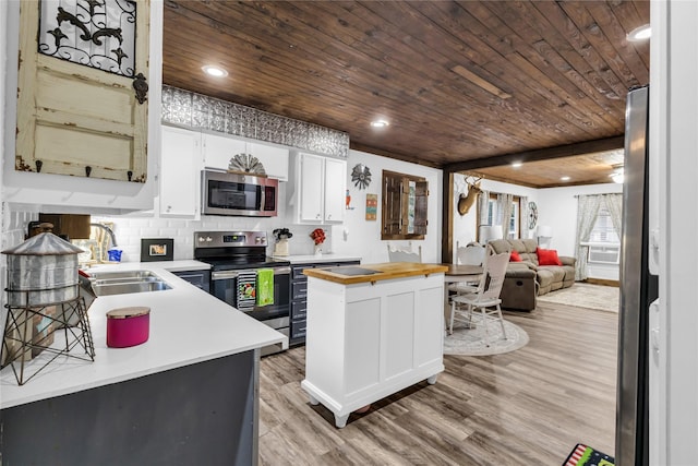 kitchen with butcher block counters, white cabinetry, sink, light hardwood / wood-style floors, and appliances with stainless steel finishes