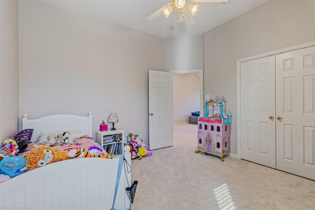 bedroom with ceiling fan, light colored carpet, and a closet