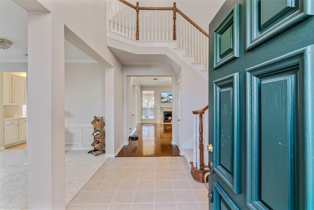 foyer with crown molding, a towering ceiling, and carpet floors