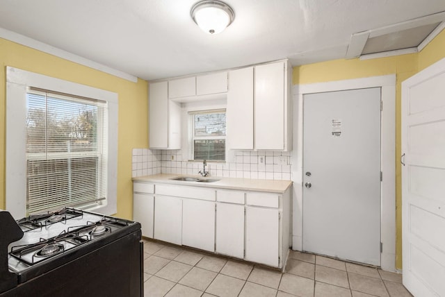 kitchen with decorative backsplash, gas stove, white cabinetry, and a healthy amount of sunlight