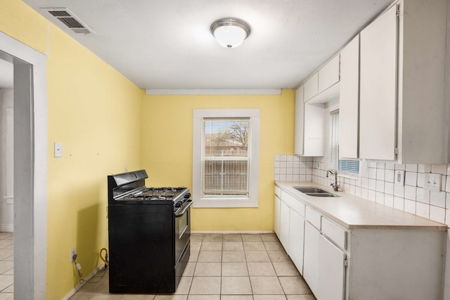 kitchen with black gas range, backsplash, sink, and white cabinets