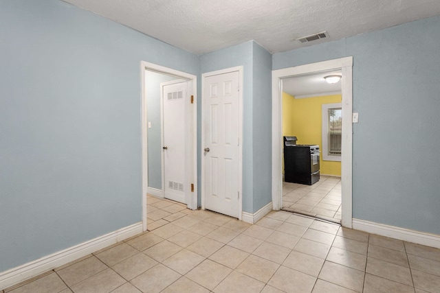 spare room with light tile patterned flooring and a textured ceiling