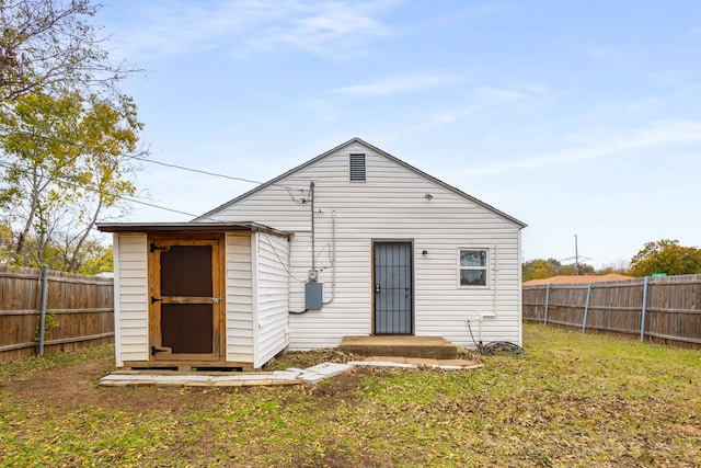 back of house featuring a yard and a storage unit