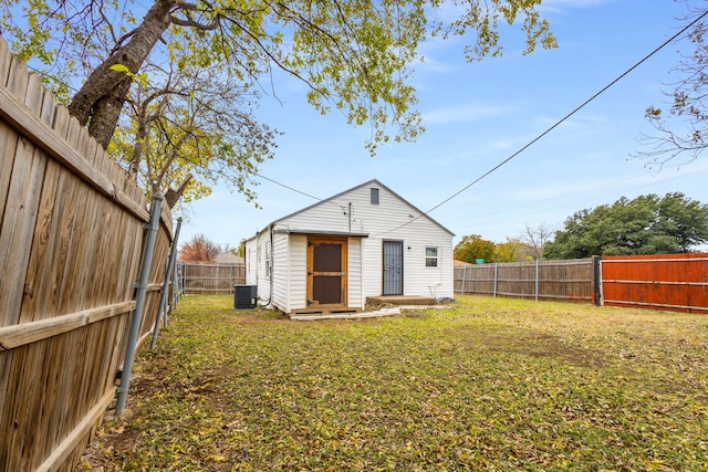 back of house with an outbuilding, a yard, and central AC unit