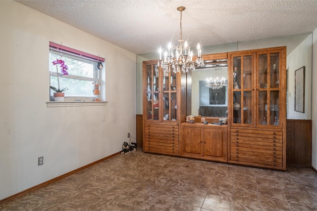 unfurnished dining area featuring a chandelier and a textured ceiling