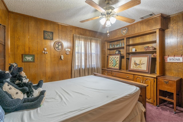 carpeted bedroom with ceiling fan, a textured ceiling, and wooden walls