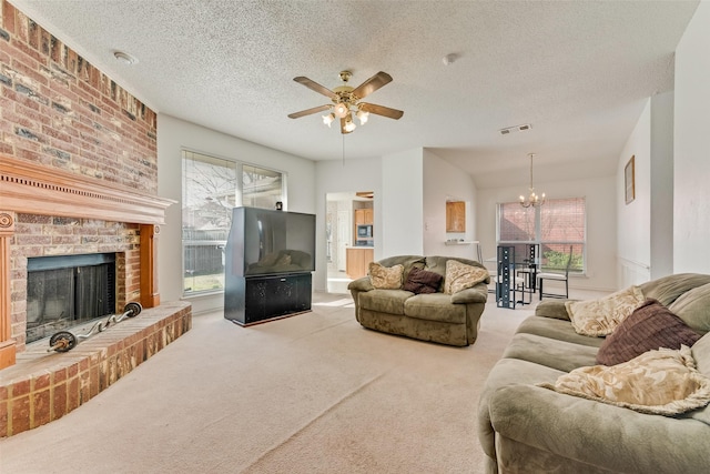 living room with light carpet, ceiling fan with notable chandelier, a textured ceiling, and a brick fireplace