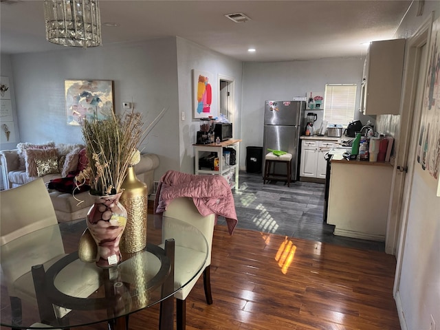 dining area featuring dark hardwood / wood-style flooring and an inviting chandelier