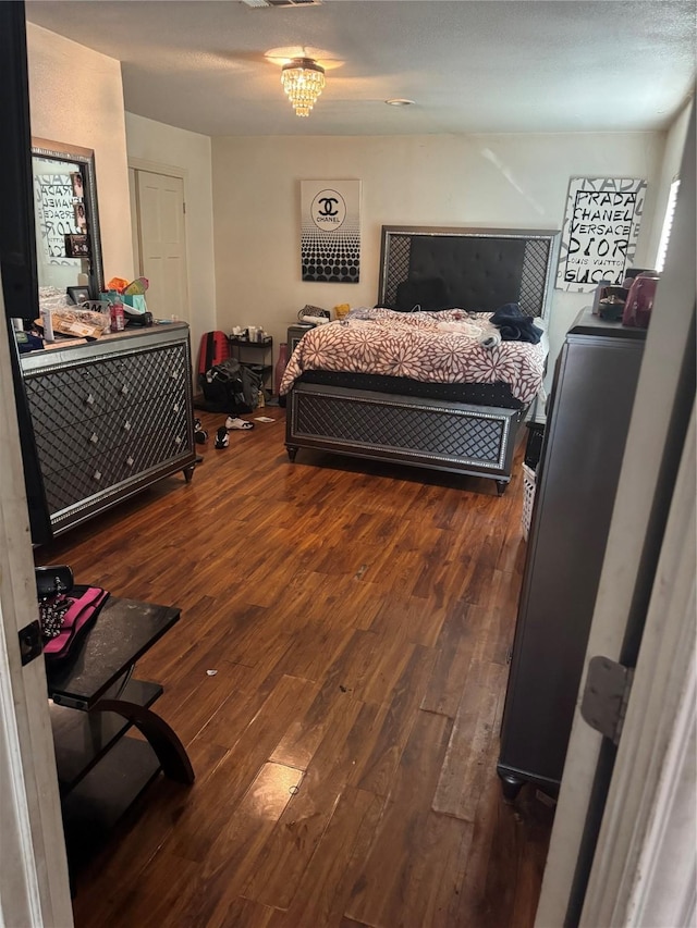 bedroom with a chandelier and dark hardwood / wood-style flooring