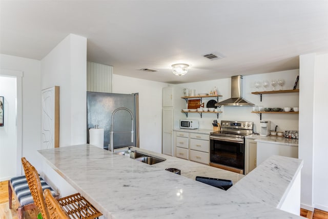 kitchen featuring light stone countertops, stainless steel appliances, extractor fan, sink, and light hardwood / wood-style flooring