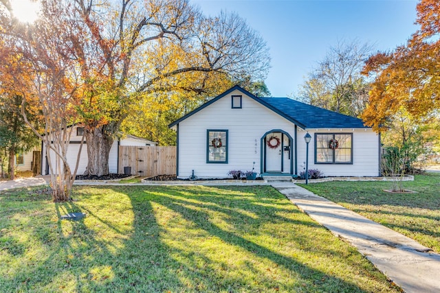 view of front of house with a garage, an outbuilding, and a front lawn