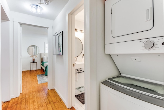 clothes washing area with stacked washer / dryer and light hardwood / wood-style floors