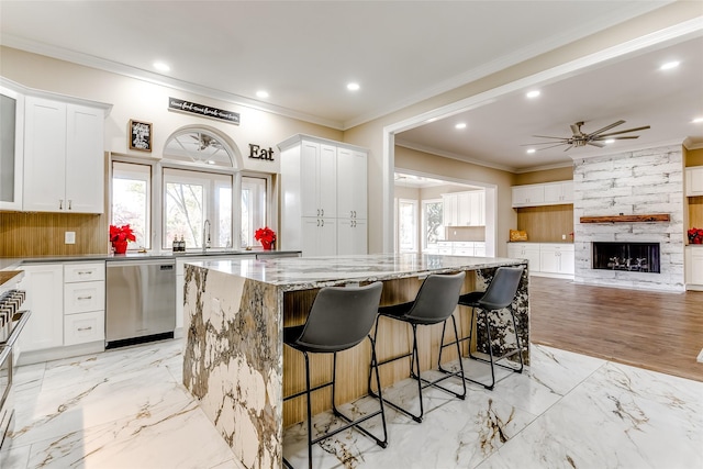 kitchen featuring white cabinets, a kitchen island, stainless steel dishwasher, and a healthy amount of sunlight