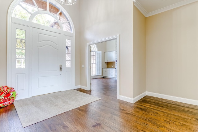 foyer entrance featuring dark hardwood / wood-style flooring, an inviting chandelier, and ornamental molding