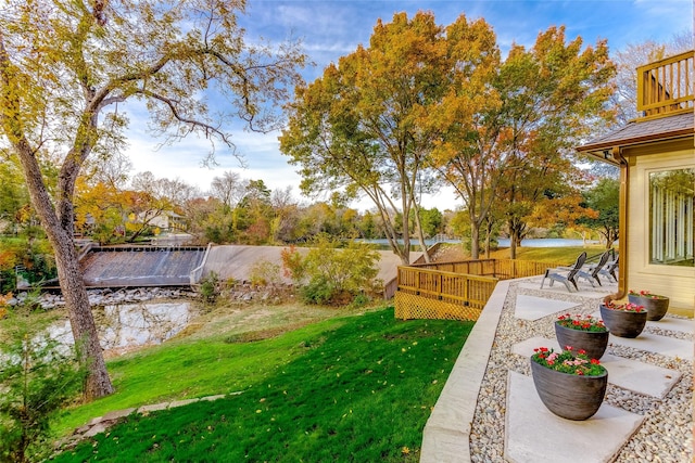 view of yard featuring a deck with water view and a patio