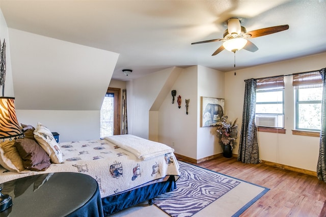 bedroom featuring light hardwood / wood-style floors, multiple windows, cooling unit, and ceiling fan