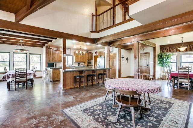 dining space with beamed ceiling, a healthy amount of sunlight, and a chandelier