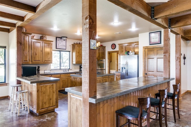 kitchen with a breakfast bar, appliances with stainless steel finishes, kitchen peninsula, and beamed ceiling