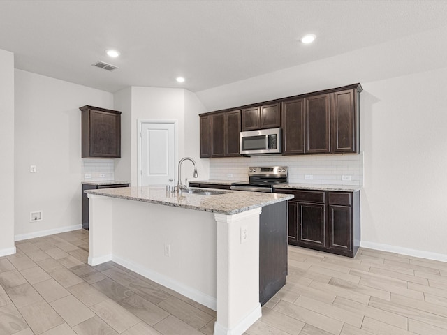 kitchen with decorative backsplash, stainless steel appliances, a center island with sink, and sink