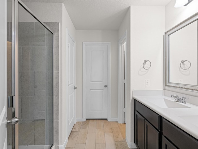 bathroom featuring a textured ceiling, vanity, and an enclosed shower