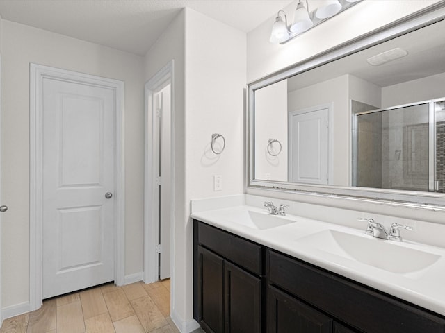 bathroom with wood-type flooring, vanity, and a shower with shower door