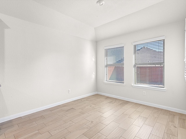 empty room with light wood-type flooring and lofted ceiling