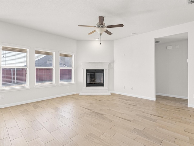 unfurnished living room with a textured ceiling, light wood-type flooring, and ceiling fan