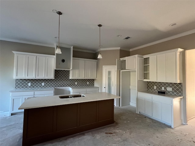 kitchen featuring backsplash, white cabinets, an island with sink, and decorative light fixtures