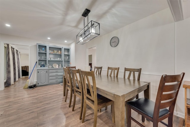 dining area with light wood-type flooring and a notable chandelier