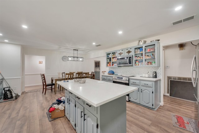 kitchen with pendant lighting, a kitchen island, stainless steel appliances, and light wood-type flooring