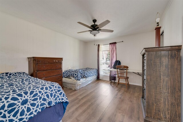 bedroom featuring hardwood / wood-style floors, ceiling fan, and wood walls