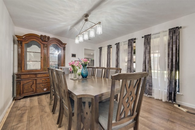 dining room with hardwood / wood-style flooring, a healthy amount of sunlight, and an inviting chandelier