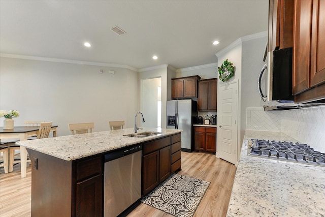 kitchen featuring tasteful backsplash, stainless steel appliances, a kitchen island with sink, sink, and light hardwood / wood-style floors