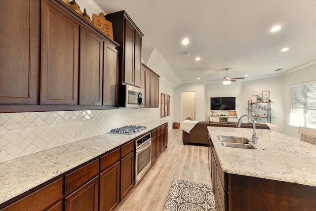 kitchen featuring sink, ornamental molding, appliances with stainless steel finishes, tasteful backsplash, and light hardwood / wood-style floors