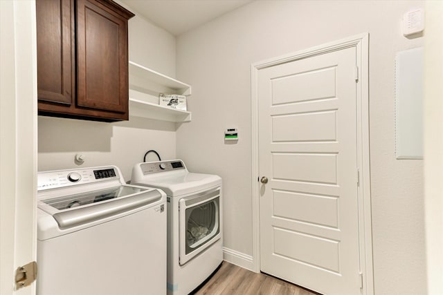 laundry room with separate washer and dryer, cabinets, and light wood-type flooring